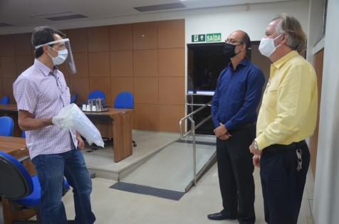 Fernando Souza faz a entrega dos protetores faciais aos gestores da UFU, Valder Steffen, e do HC, Nilton Pereira (Foto: Alexandre Costa)